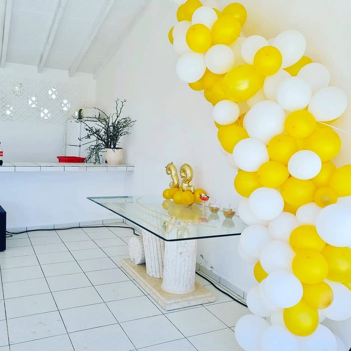 Arche de ballons jaune et blanc au-dessus d'une table à gâteau